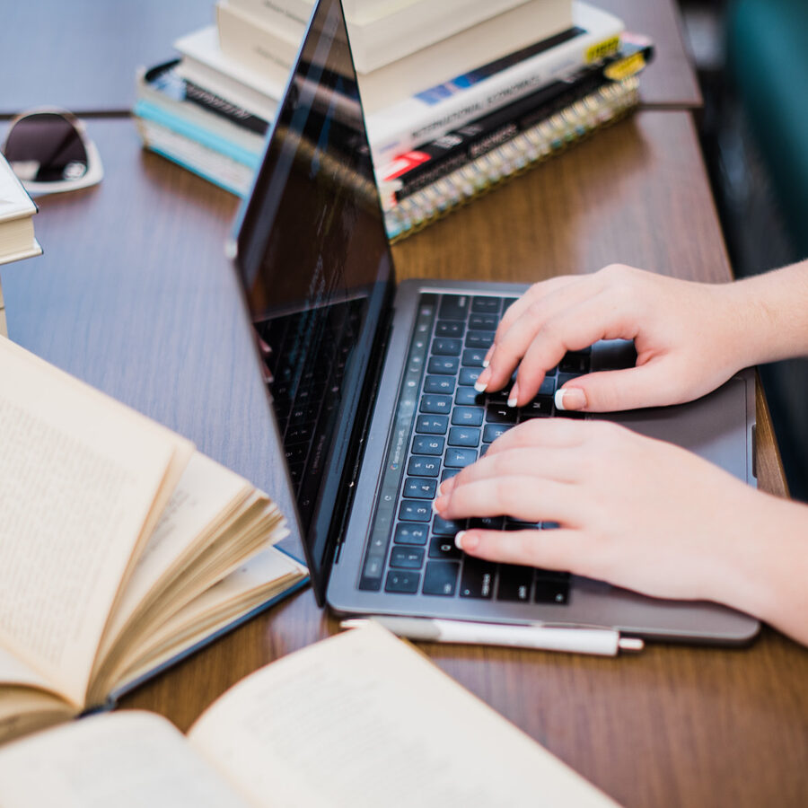 open books on table, student working on laptop, aerial shot