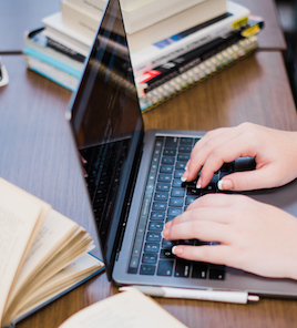 open books on table, student working on laptop, aerial shot