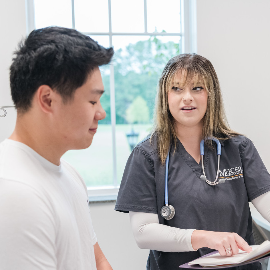 Mercer BSN student in scrubs conversing with patient