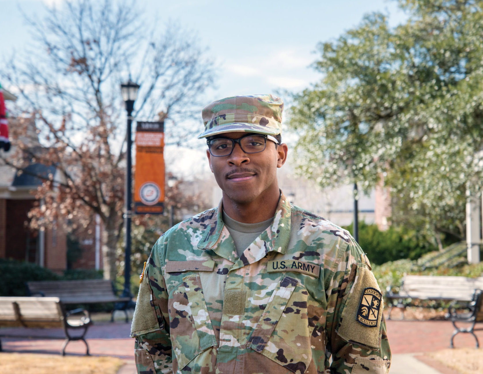 service member on mercer campus, orange mercer banner in background
