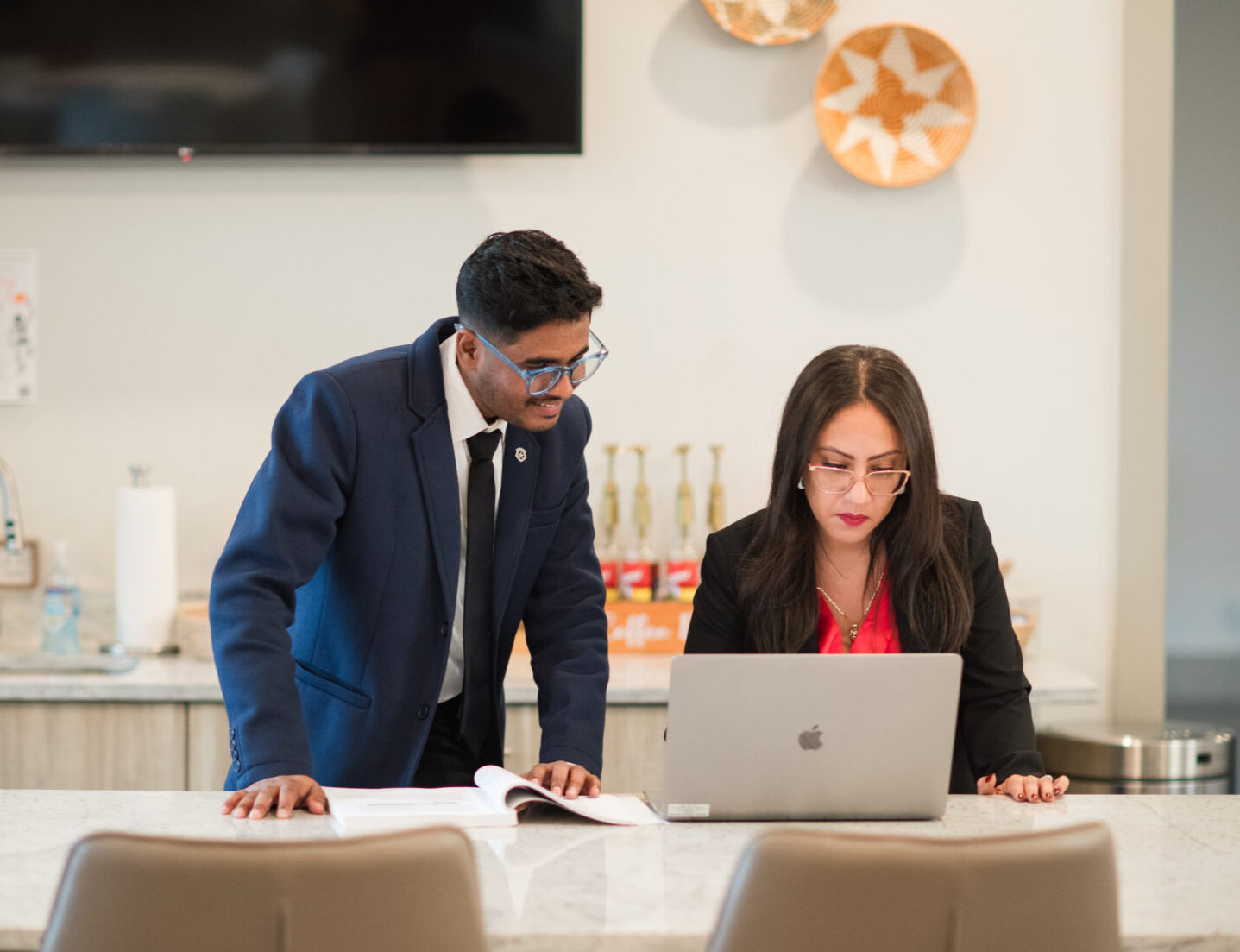 two students in business professional attire looking at laptop